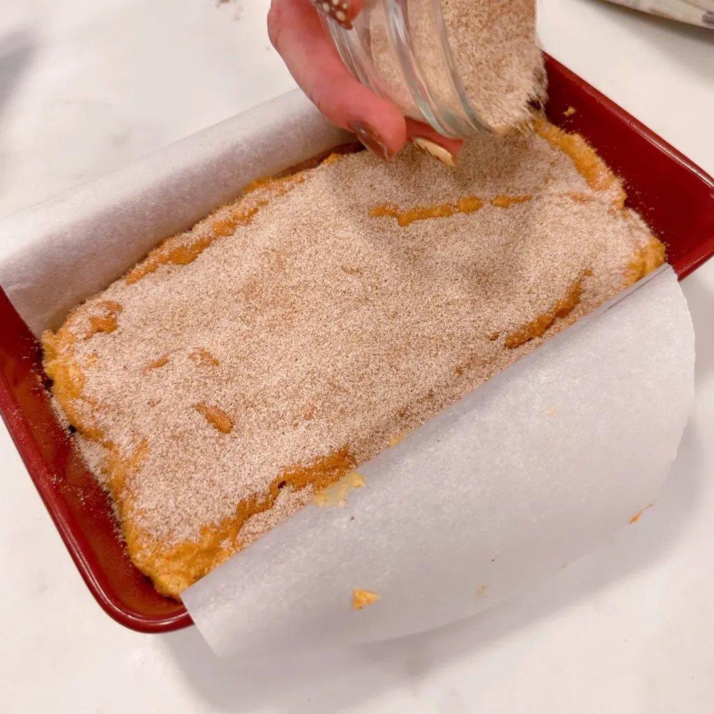 Sprinkling cinnamon sugar over sweet potato bread.