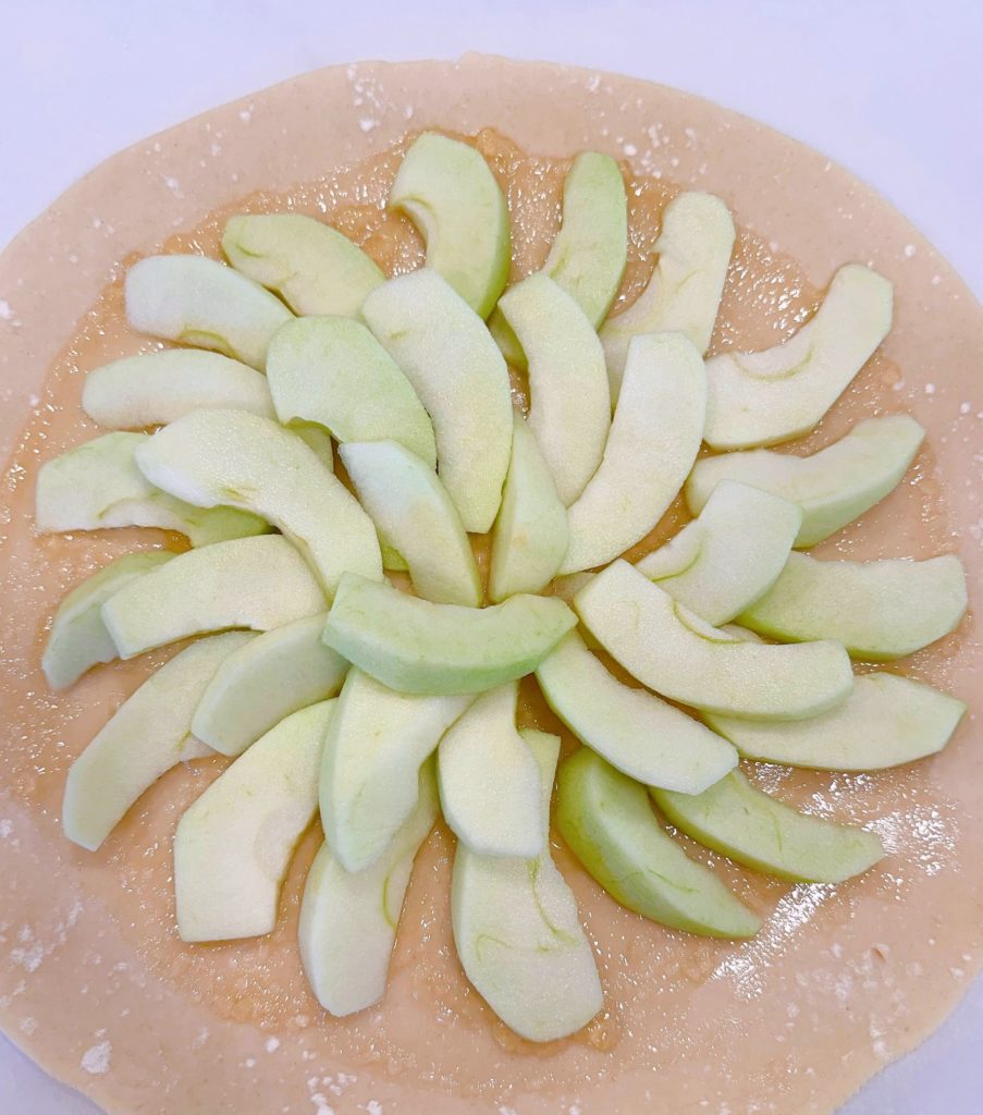 Apples arranged on the pie dough.