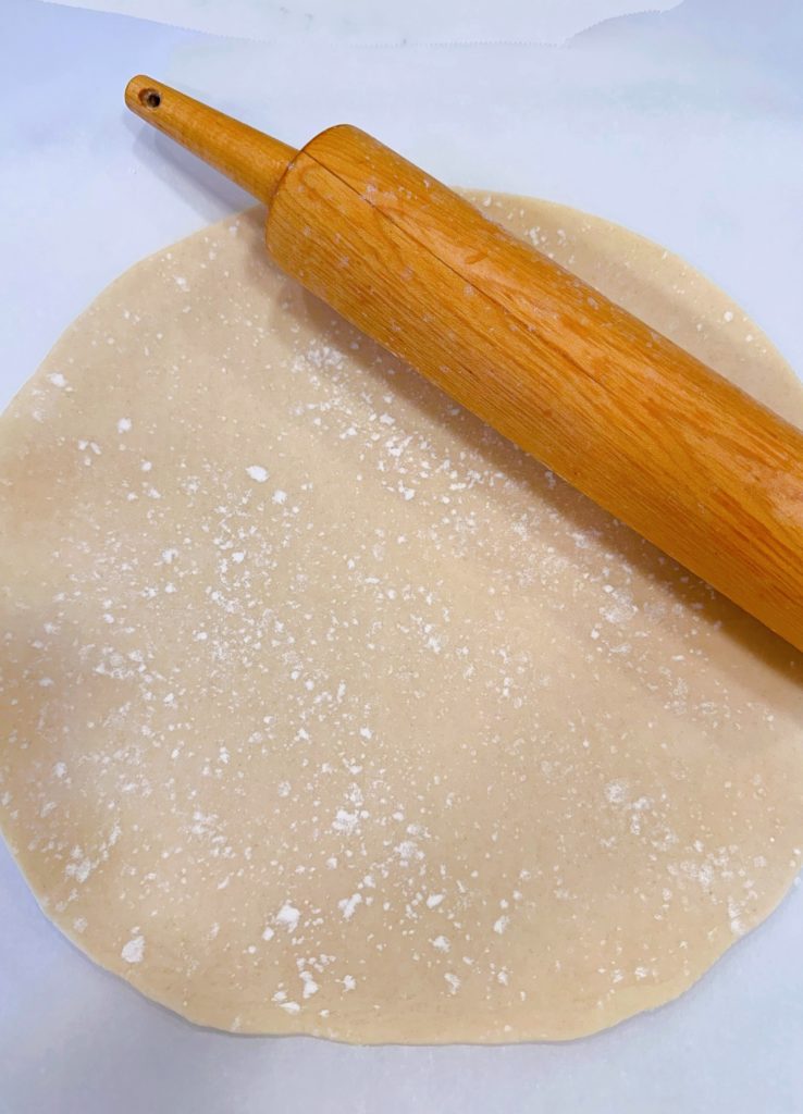 Rolling out the refrigerated pie dough into a 14-inch circle.