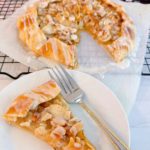 Slice of apple almond galette with a fork on a dessert plate.