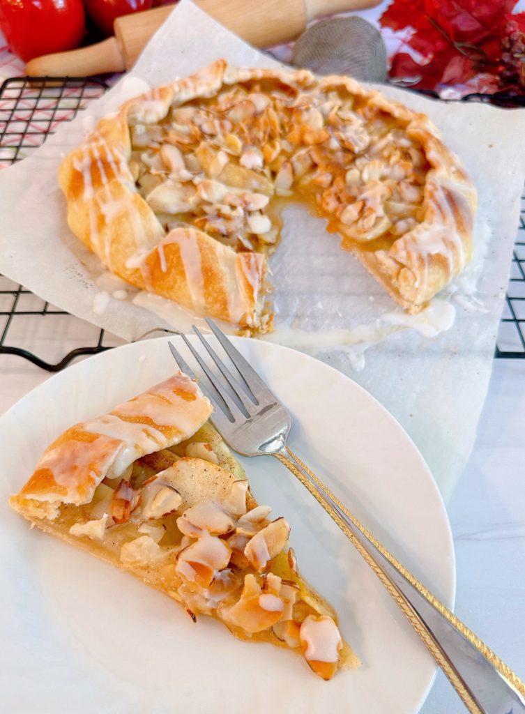 Slice of apple almond galette with a fork on a dessert plate.