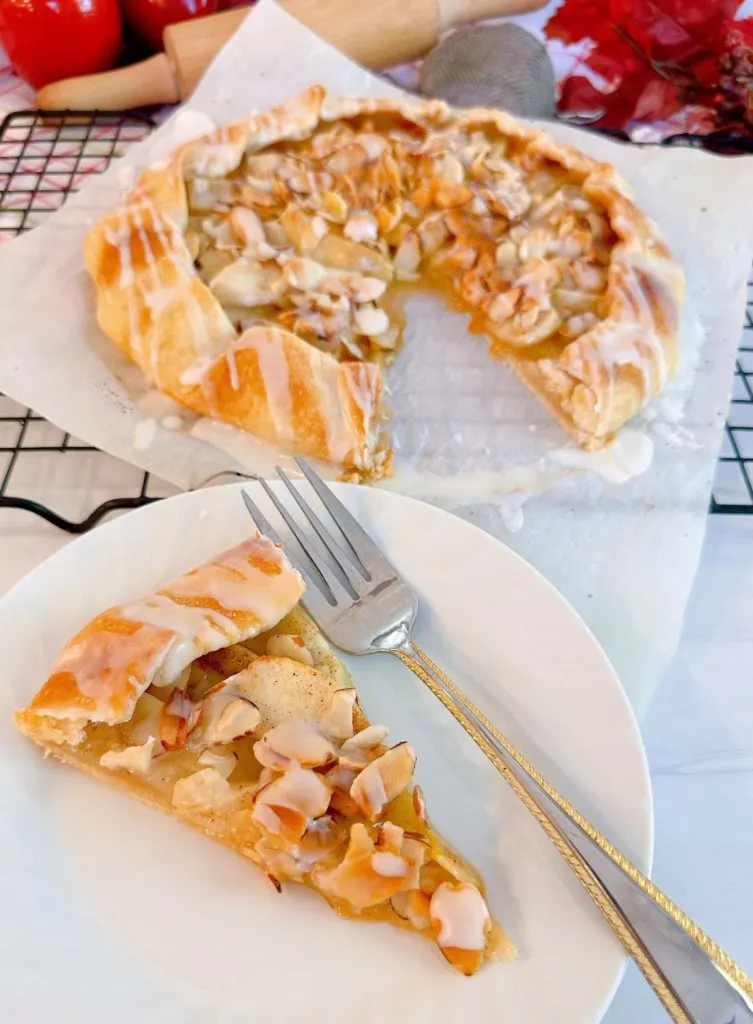 Slice of apple almond galette with a fork on a dessert plate.