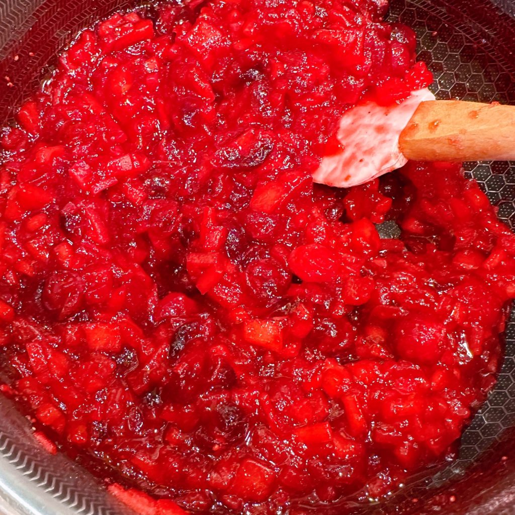 Cranberry pear raspberry chutney cooked in a large sauce pan.