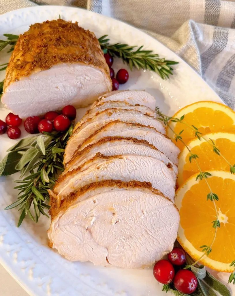 Turkey roast sliced into serving sizes on a beautiful platter with garnishes.