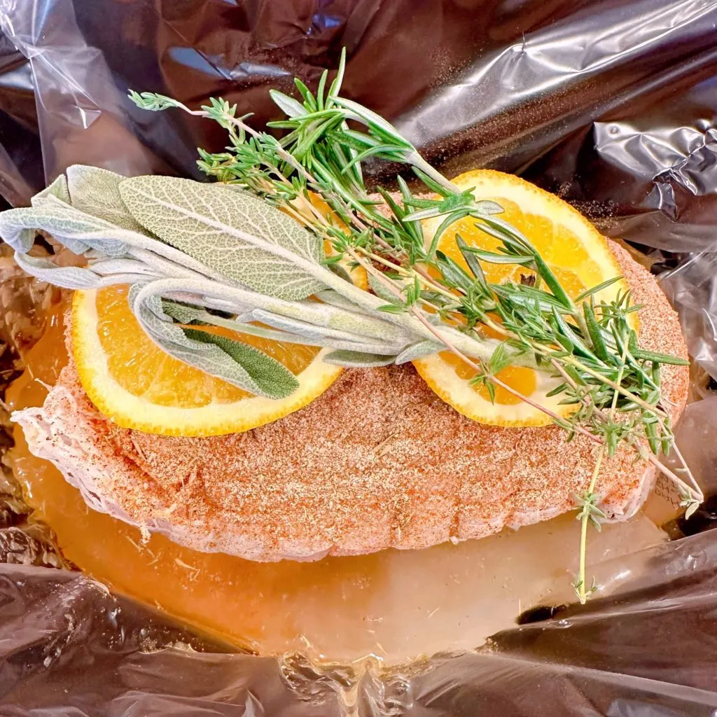 Turkey roast topped with orange slices, and fresh sprigs of herbs.