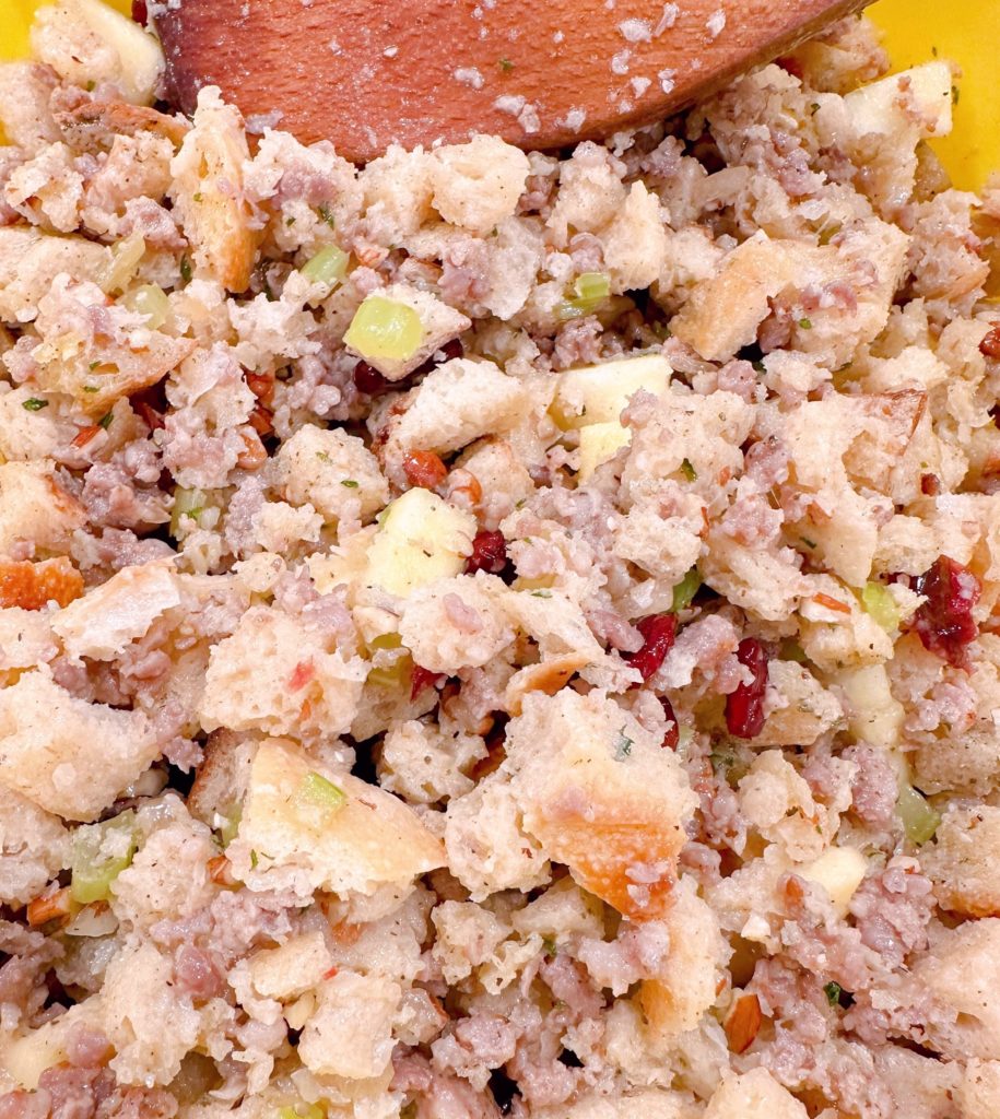 Mixing all the stuffing ingredients together with a wooden spoon in a large bowl.