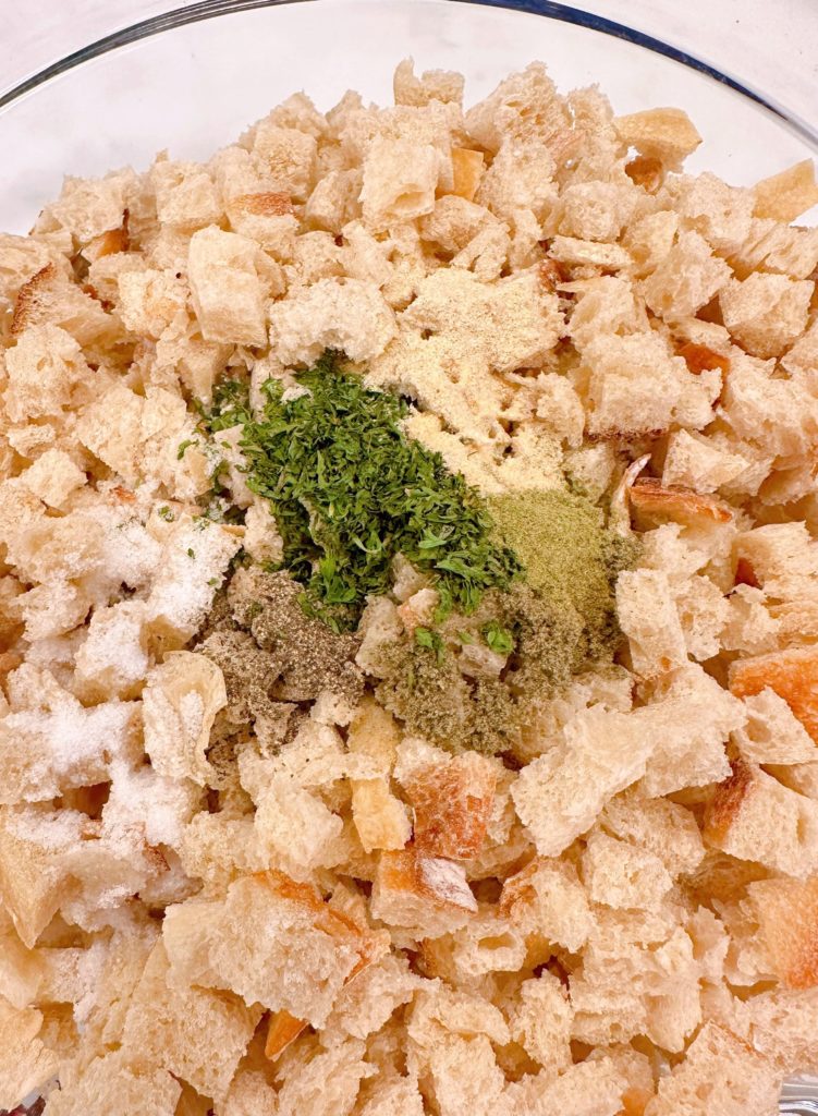 Bread cubes and seasonings in a large bowl.