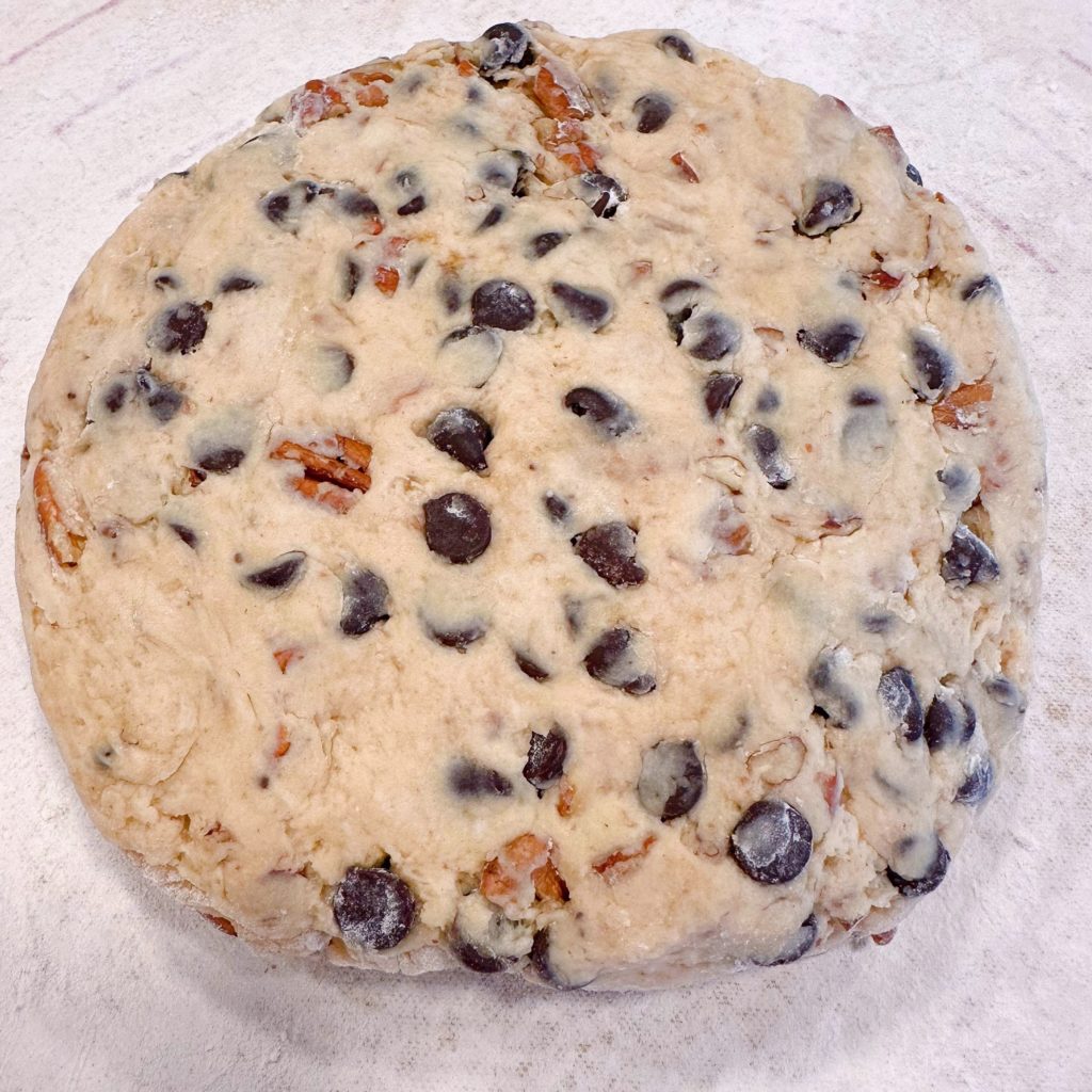 Chocolate Chip Pecan scone dough shapped into a round disc on a floured surface.