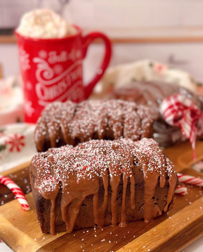 Two mini loaves of Chocolate Peppermint Loaf Cakes on a cutting board with candy canes.