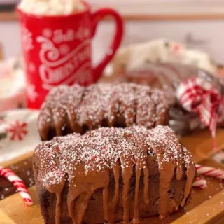 Two mini loaves of Chocolate Peppermint Loaf Cakes on a cutting board with candy canes.