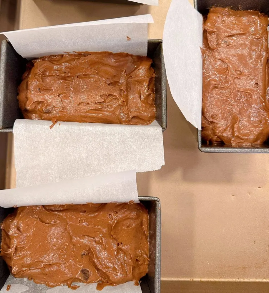 Parchment lined baking pans with cake batter.