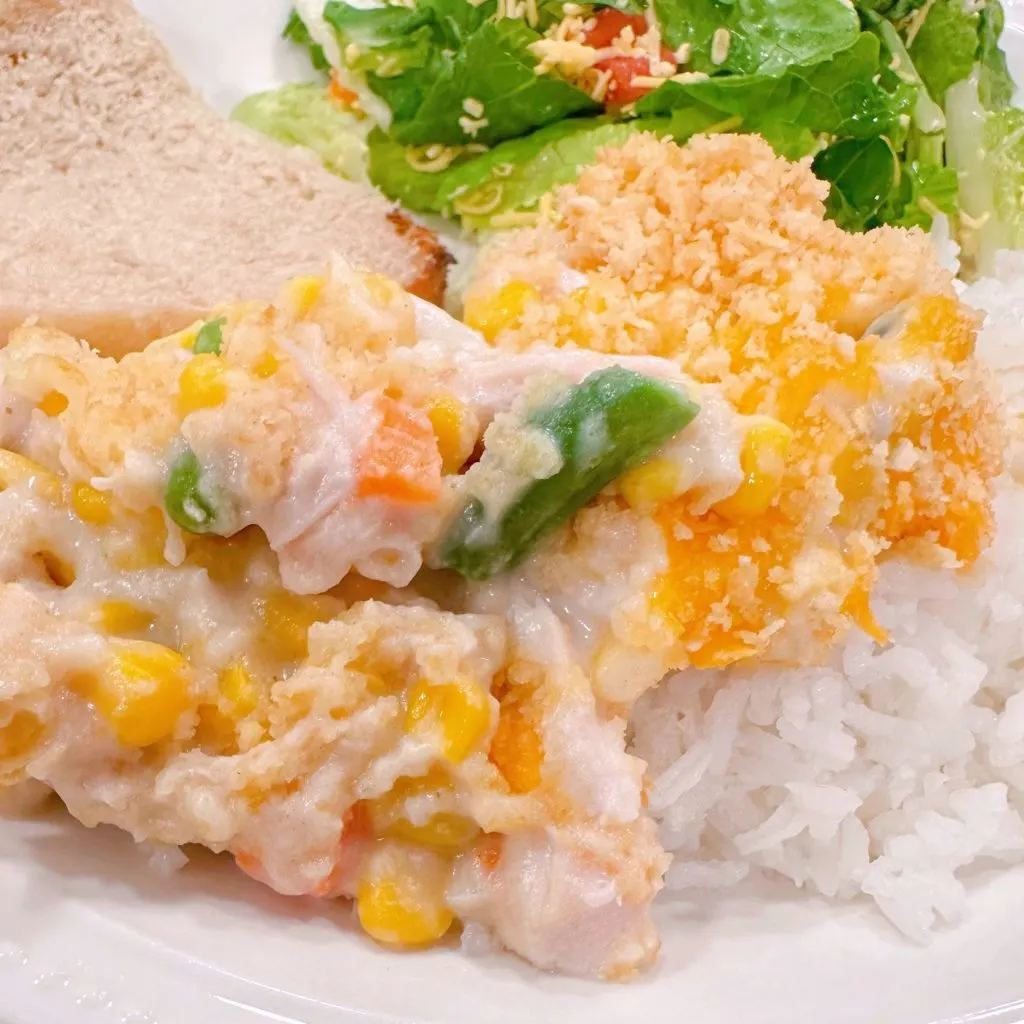 Chicken and Corn Amish Casserole served over rice on a dinner plate.