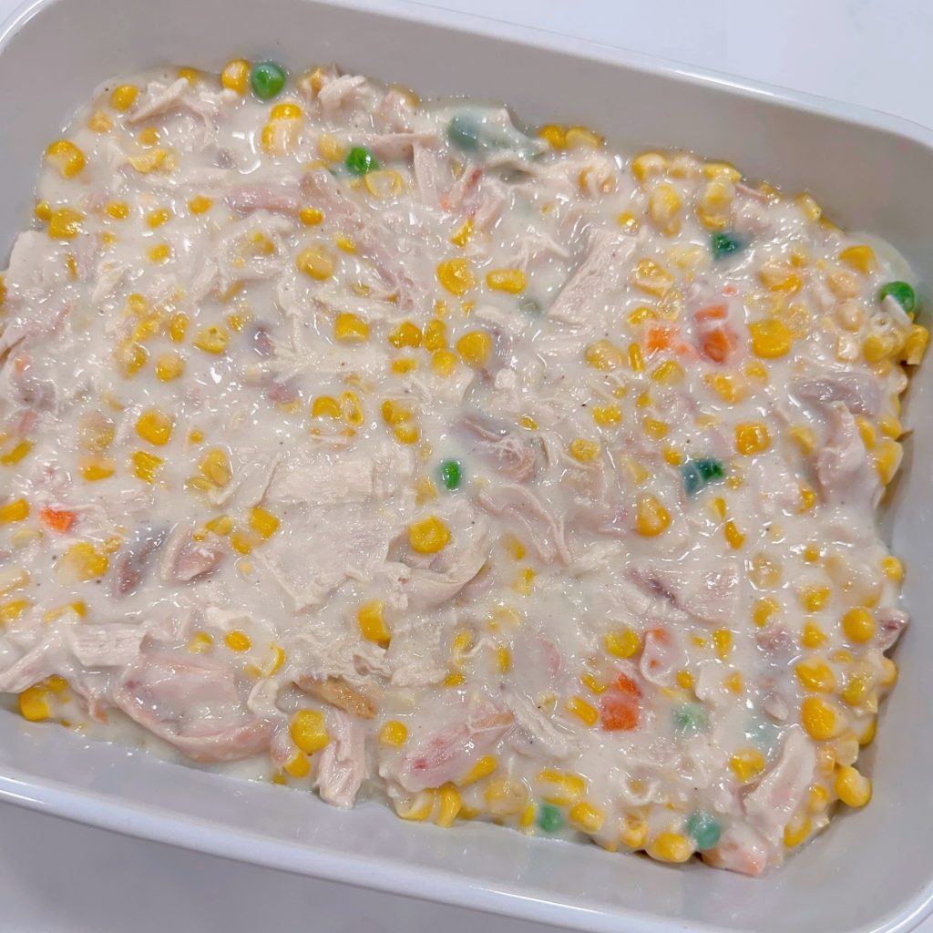 Adding chicken mixture to the prepared casserole dish.