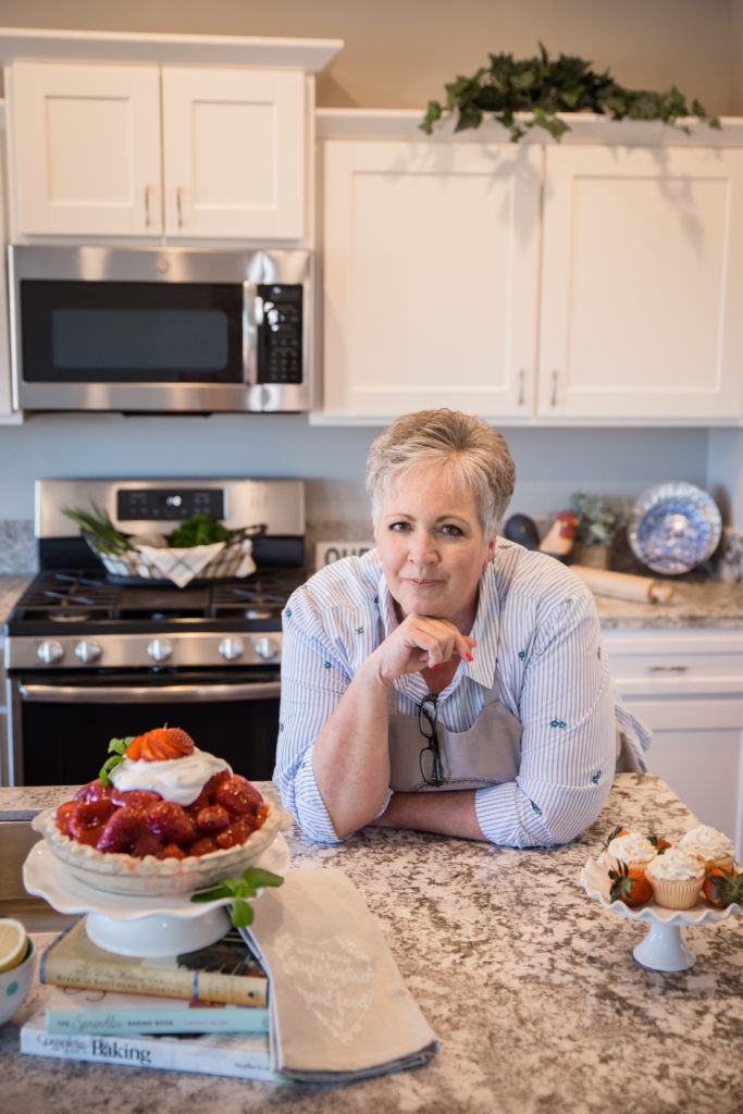 Norine Leaning on the kitchen counter with a strawberry pie.