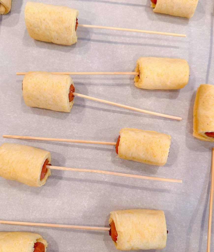 Mini little smokies wrapped in cornbread wrap with a stick in the end of each one.