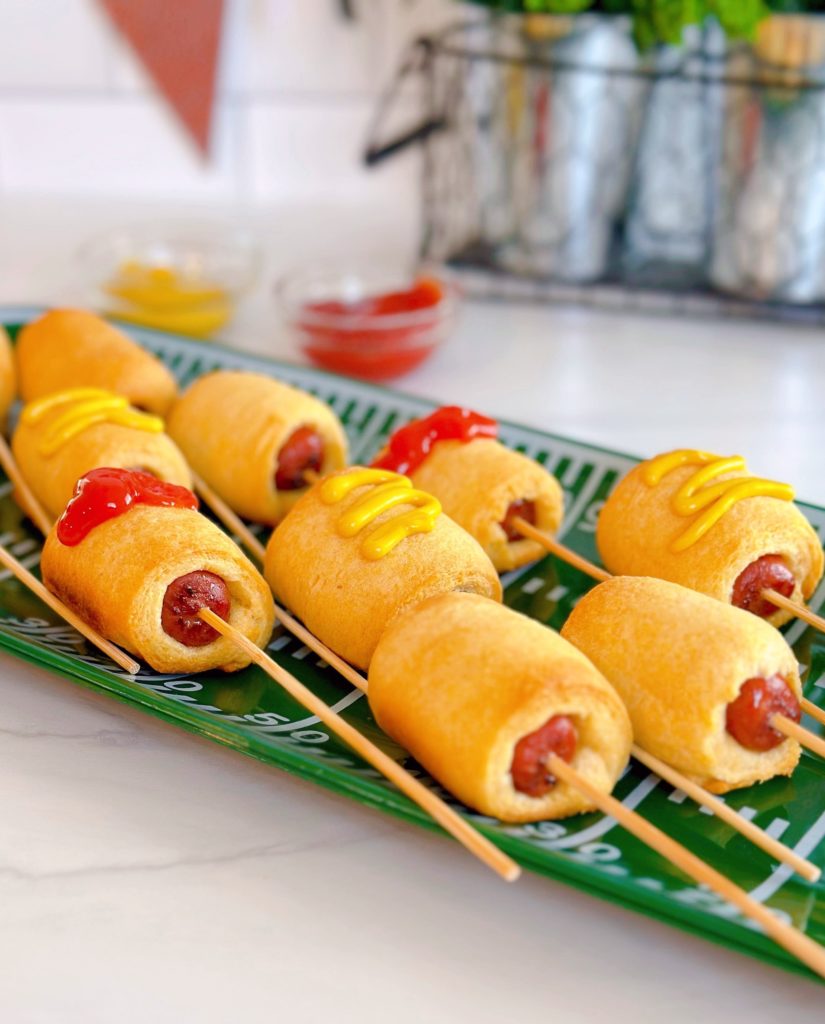 Easy 2 ingredient mini-corn dogs on a football platter with ketchup and mustard.