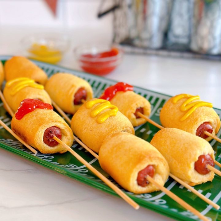 Easy 2 ingredient mini-corn dogs on a football platter with ketchup and mustard.