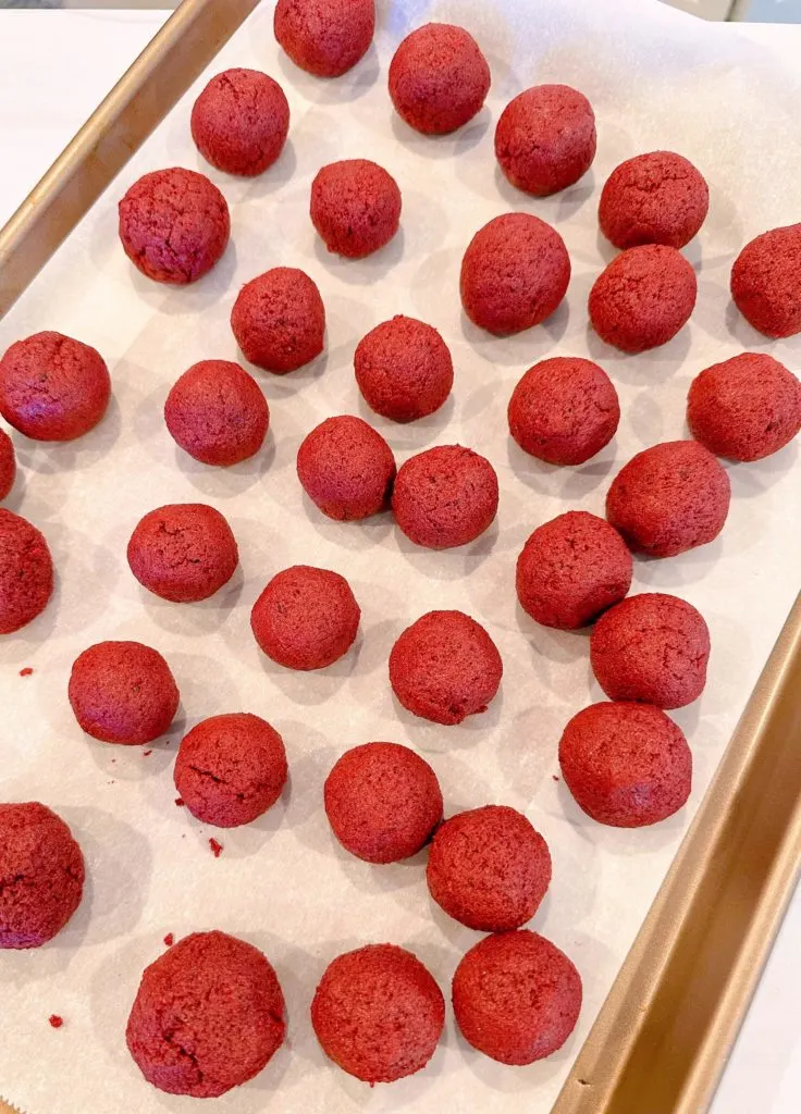 Cake balls are rolled and placed on a parchment-lined baking sheet.