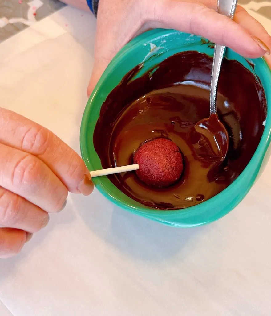 Dipping cake pops into melted chocolate.