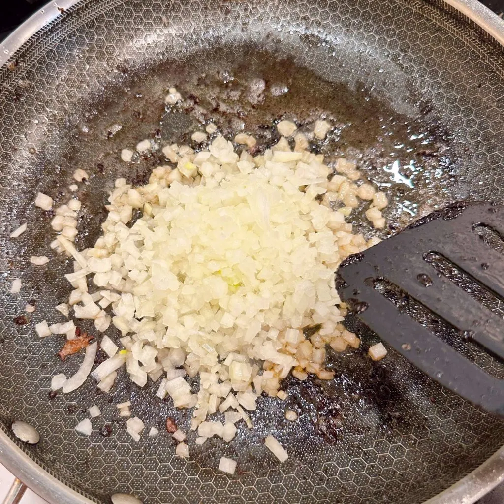 Caramelizing the diced onions in the bacon grease.