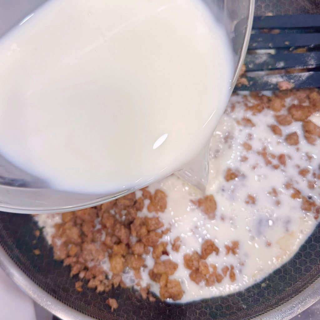 Adding milk to sausage and flour mixture.