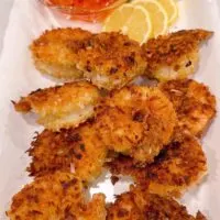 Coconut Shrimp with lemon slices on a white serving platter.