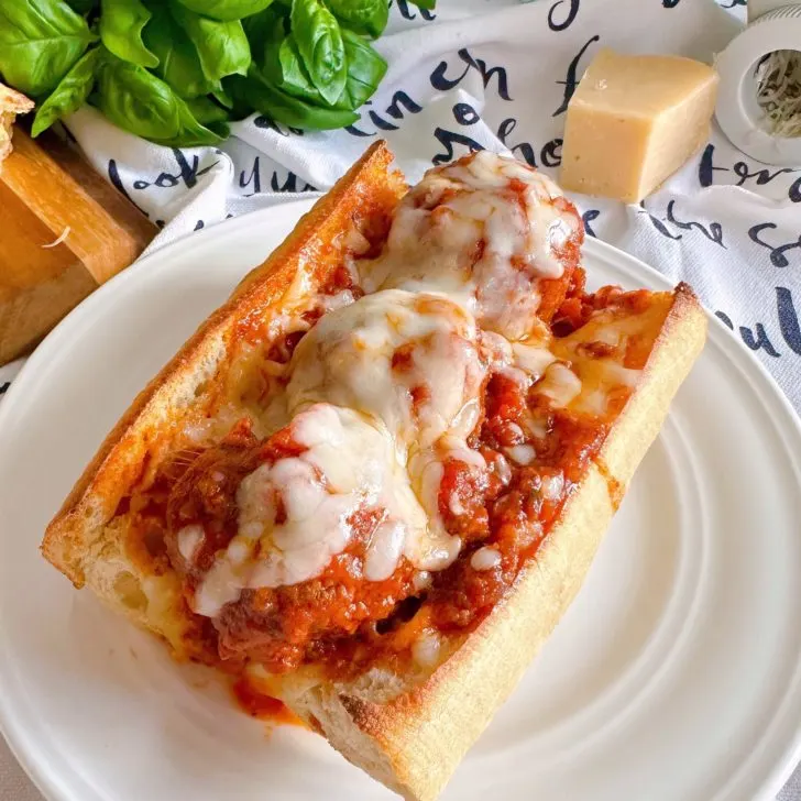 Meatball sub sandwiches on a plate with melted cheese.