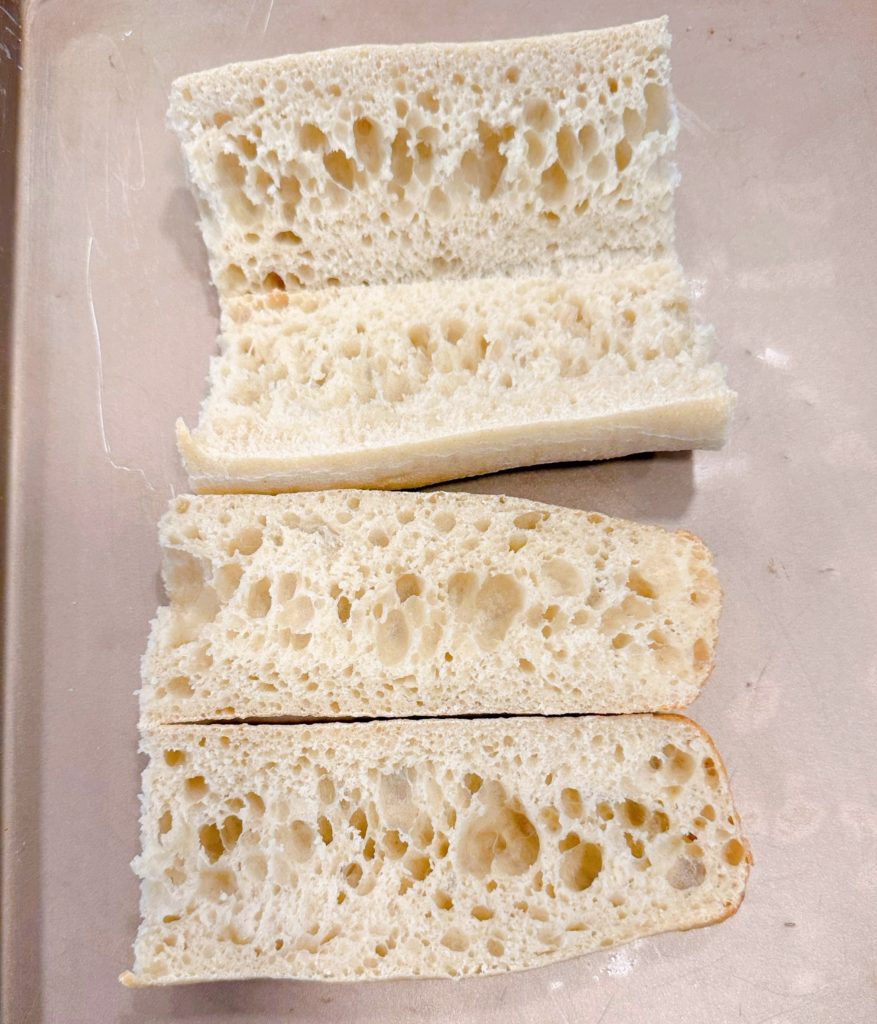 Bread on a large baking sheet lined with parchment paper for meatball sub sandwiches.