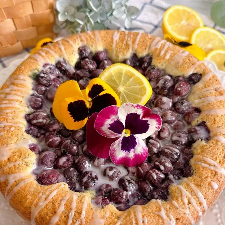 Lemon Blueberry Poppy Seed Cake with fresh pansies and lemon slices.