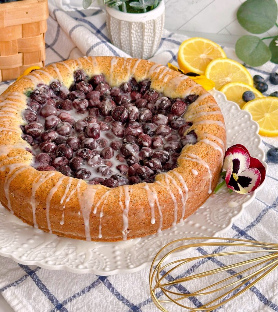 Blueberry-Lemon Poppy Seed Cake on a cake plate with citrus glaze.