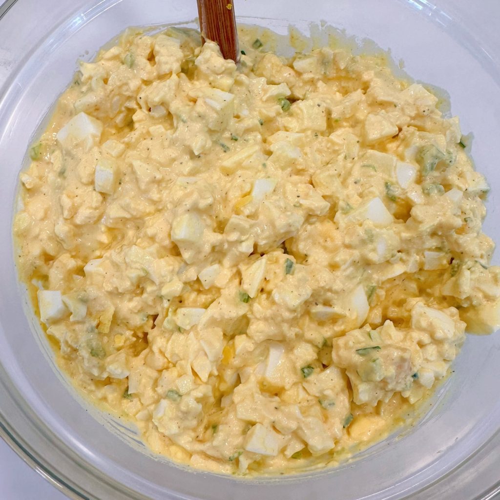 Mixed egg salad in a glass bowl.