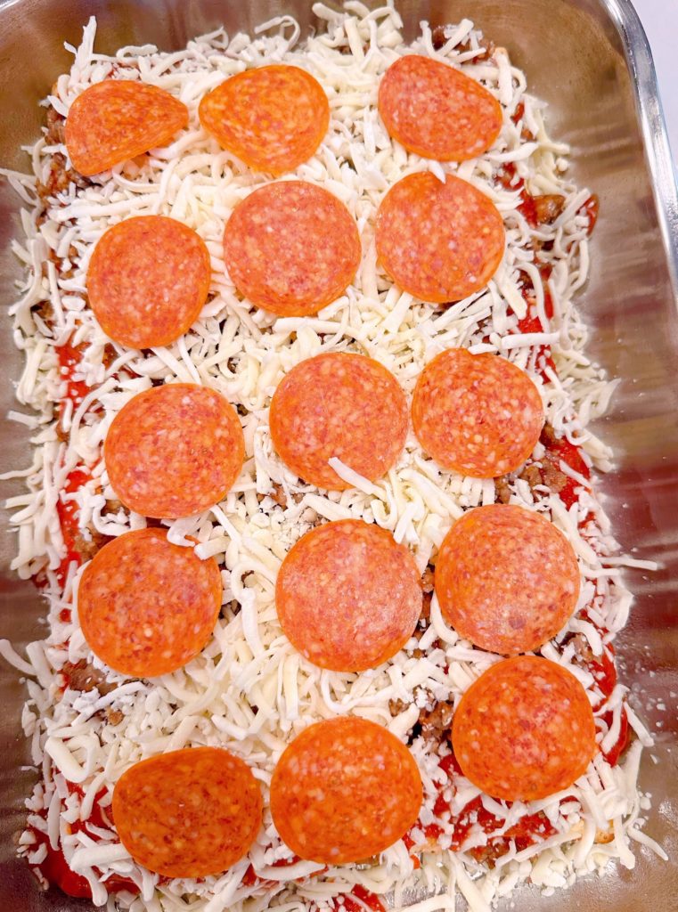 Pepperoni layered on top of cheese.